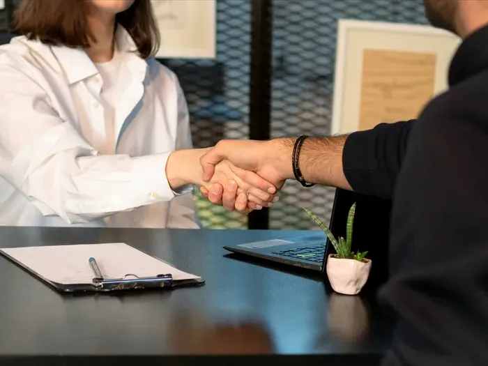 Closeup handshake across an office desk near a laptop, showing a connection between customers and local providers